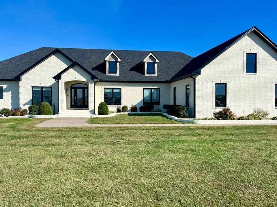 White brick home with dark roof and black trim painted exterior