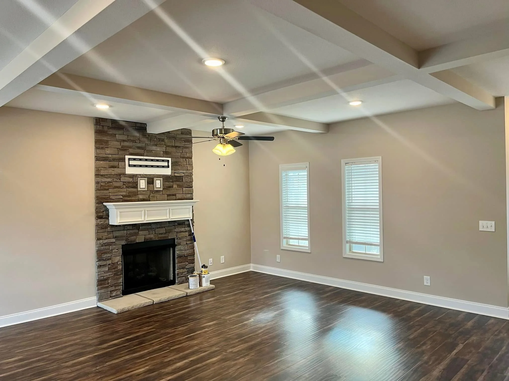 Interior room with coffered ceiling, stone fireplace, white trim, and neutral wall paint